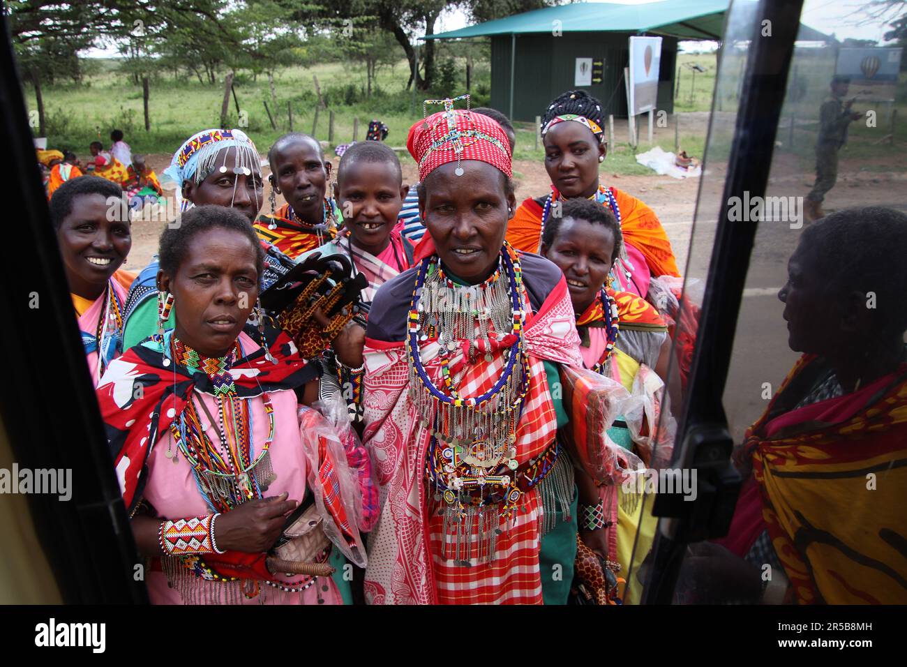 Maasai mara tribe local villagers greet tourist wearing traditional tribal dress brightly coloured colored clothing wrist bands and various necklaces Stock Photo