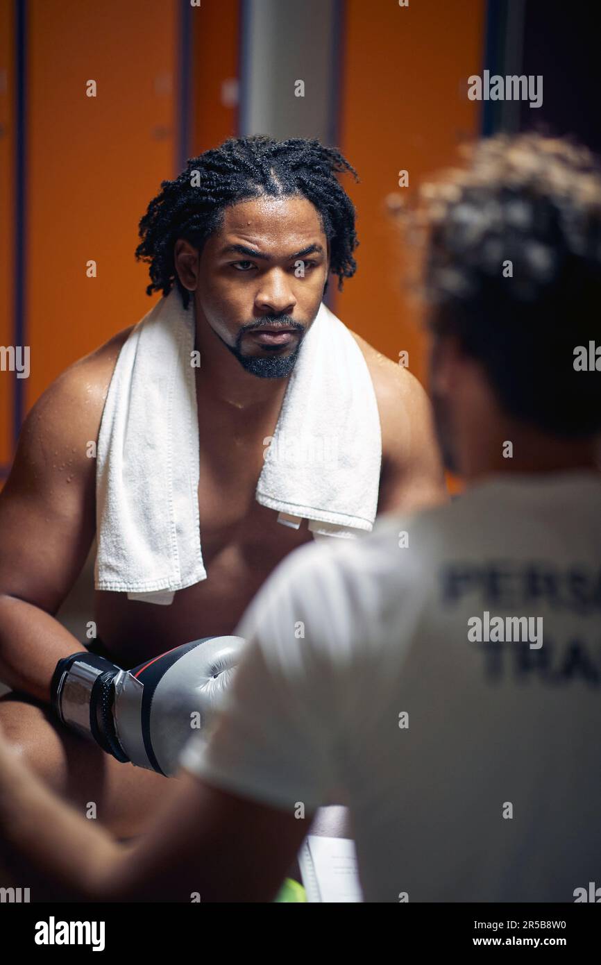 Strong and powerful young boxing player after workout sitting with