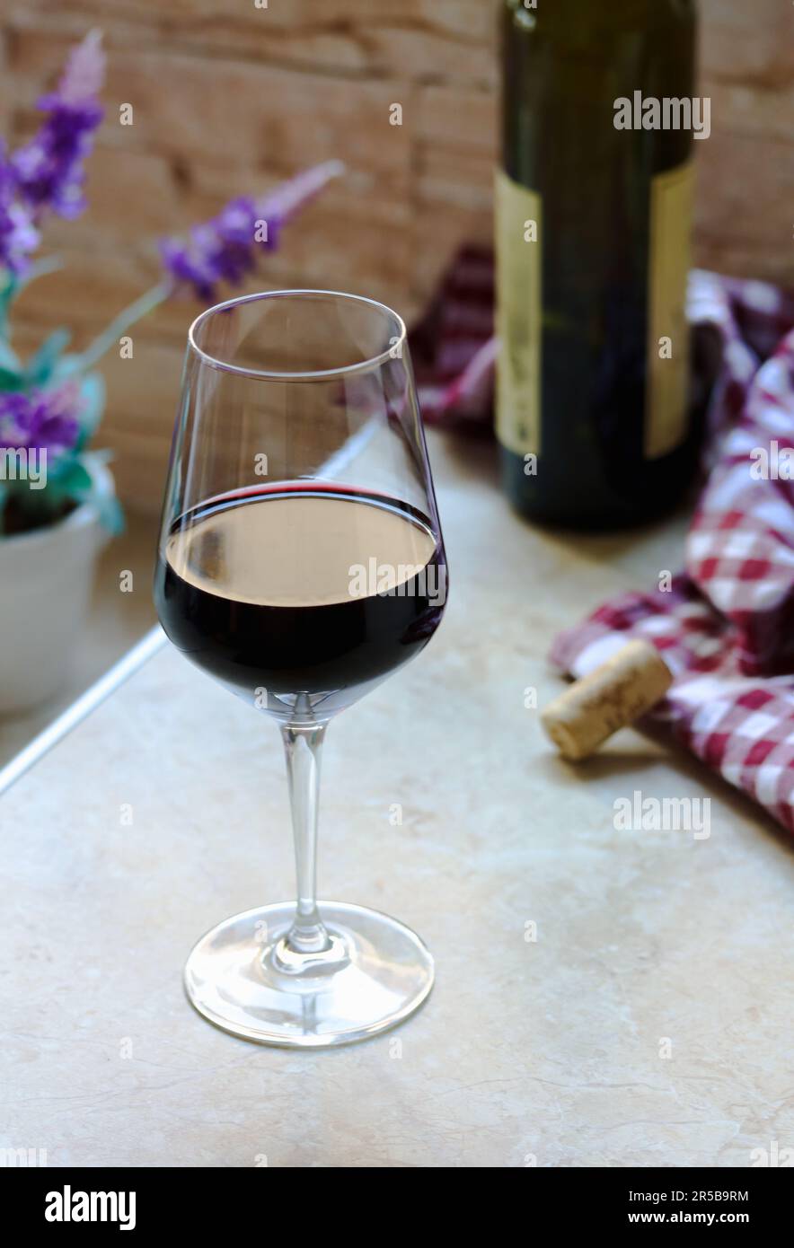 Wine glass and a bottle of red wine on table at home, cosy home atmosphere.  A