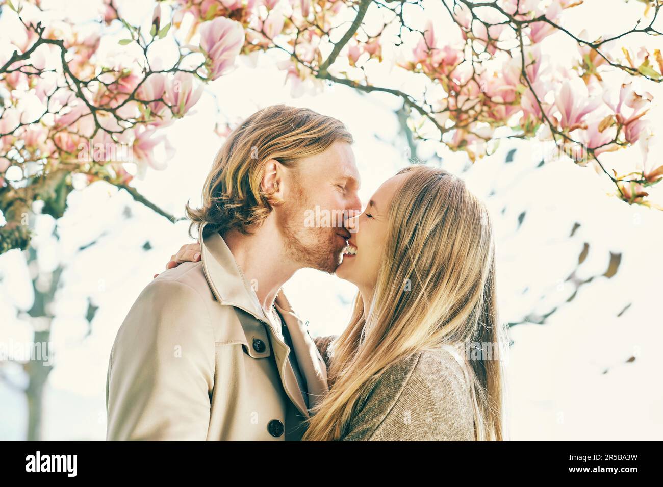 Happy romantic couple kissing under blooming tree Stock Photo - Alamy