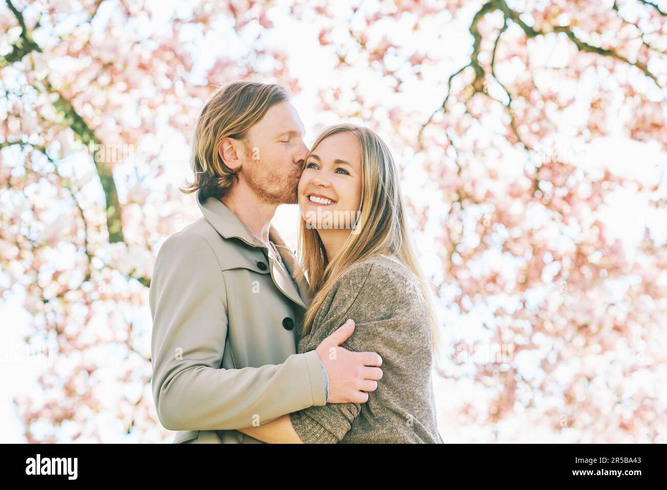Happy romantic couple kissing under blooming tree Stock Photo - Alamy