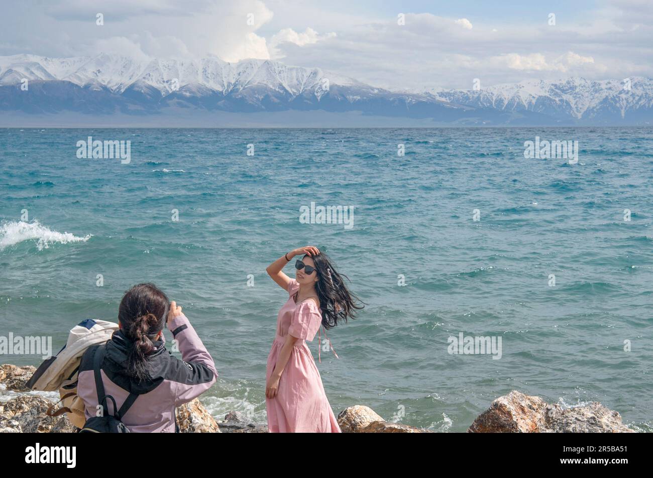 (230602) -- URUMQI, June 2, 2023 (Xinhua) -- A tourist poses for photos by the Sayram Lake in northwest China's Xinjiang Uygur Autonomous Region, May 21, 2023. According to comprehensive calculation through a big data platform for tourism statistics and sample survey, from January to April 2023, Xinjiang received over 51.19 million tourists, a year-on-year increase of 29.56%. Meanwhile, tourism revenue reached 42.64 billion yuan (about 6.03 billion U.S. dollars), up 60.59% year on year. (Xinhua/Wang Fei) Stock Photo