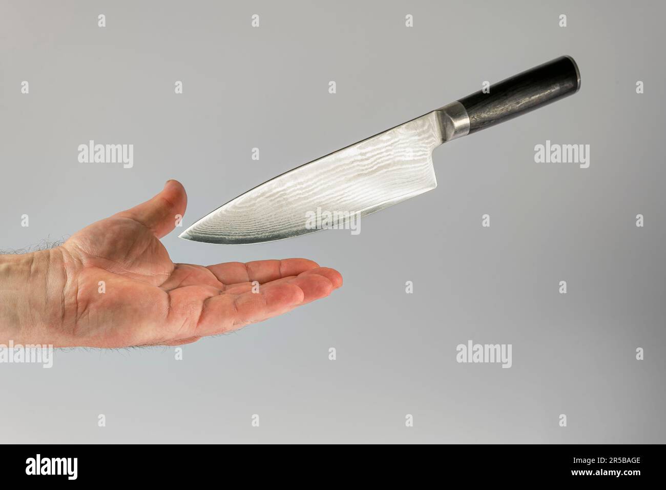 sharp kitchen knife falls with blade on male hand. Accident prevention