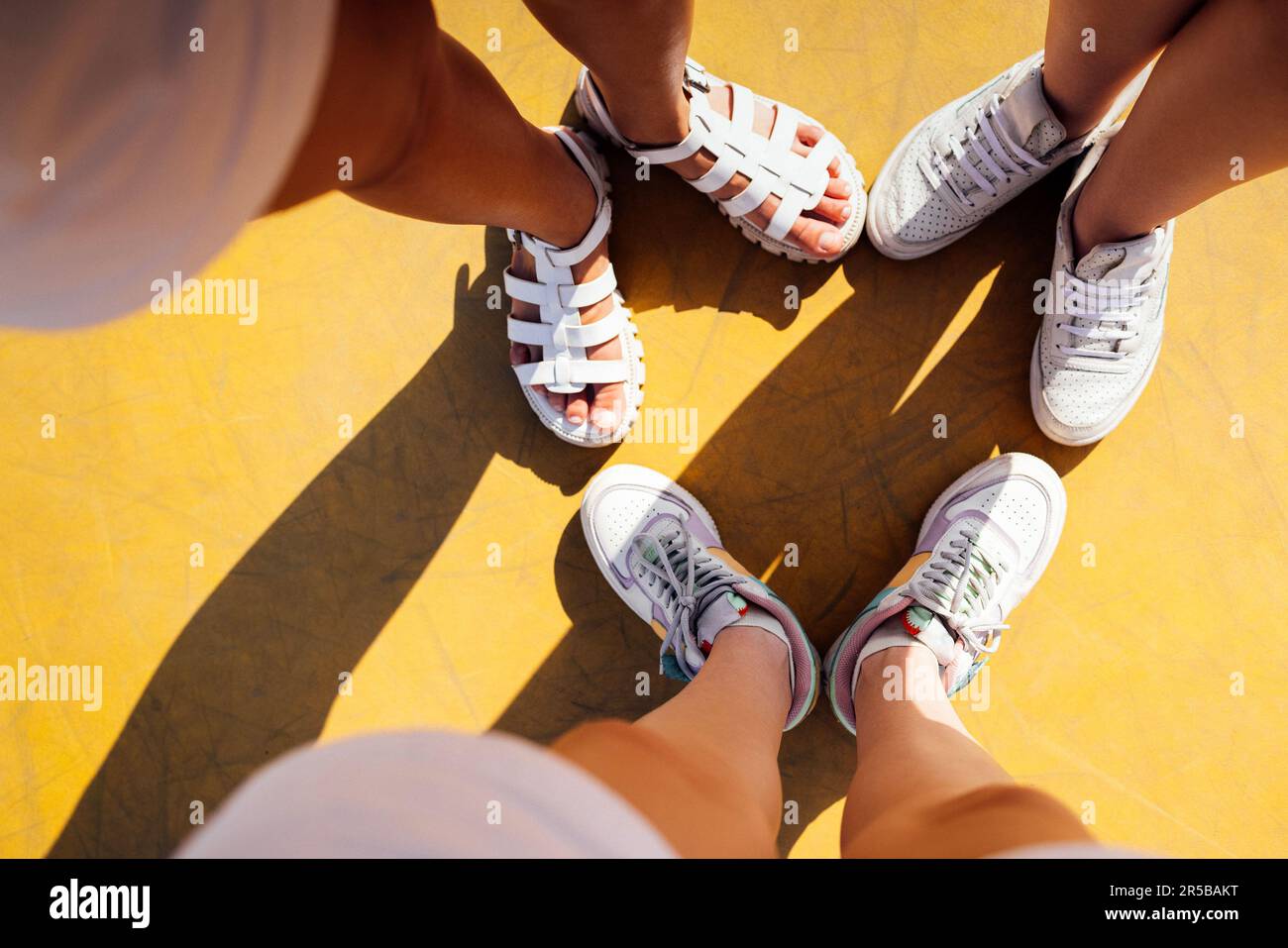 Three pairs of feet of family standing together on yellow background