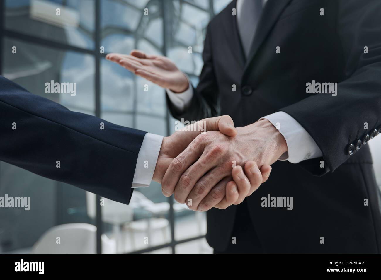 Handshake of two businessmen on the background of bright conference room, partnership concept, close up Stock Photo