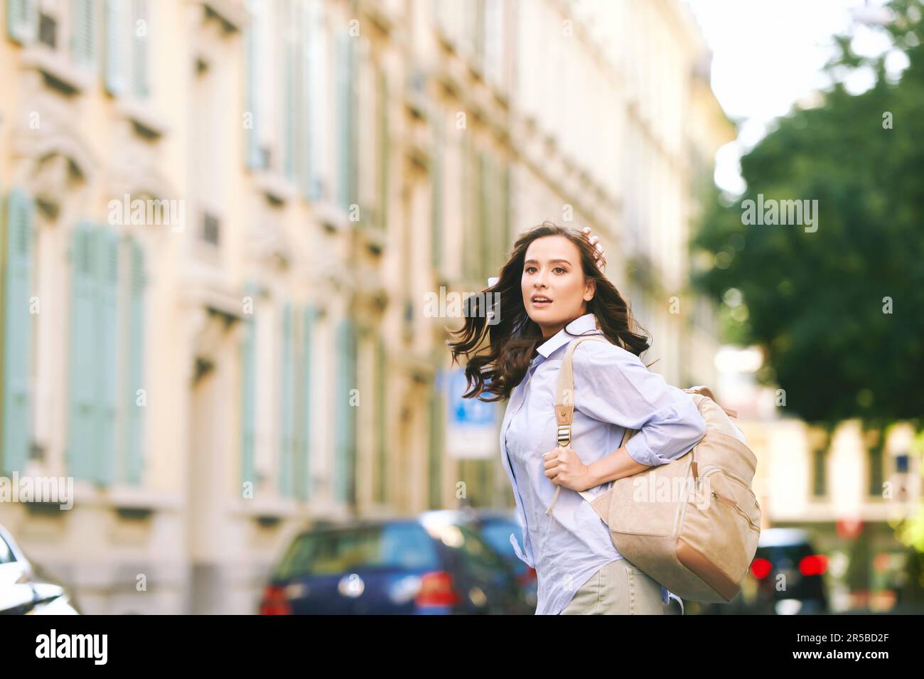 Outdoor portrait of beautiful young woman walking down the street ...