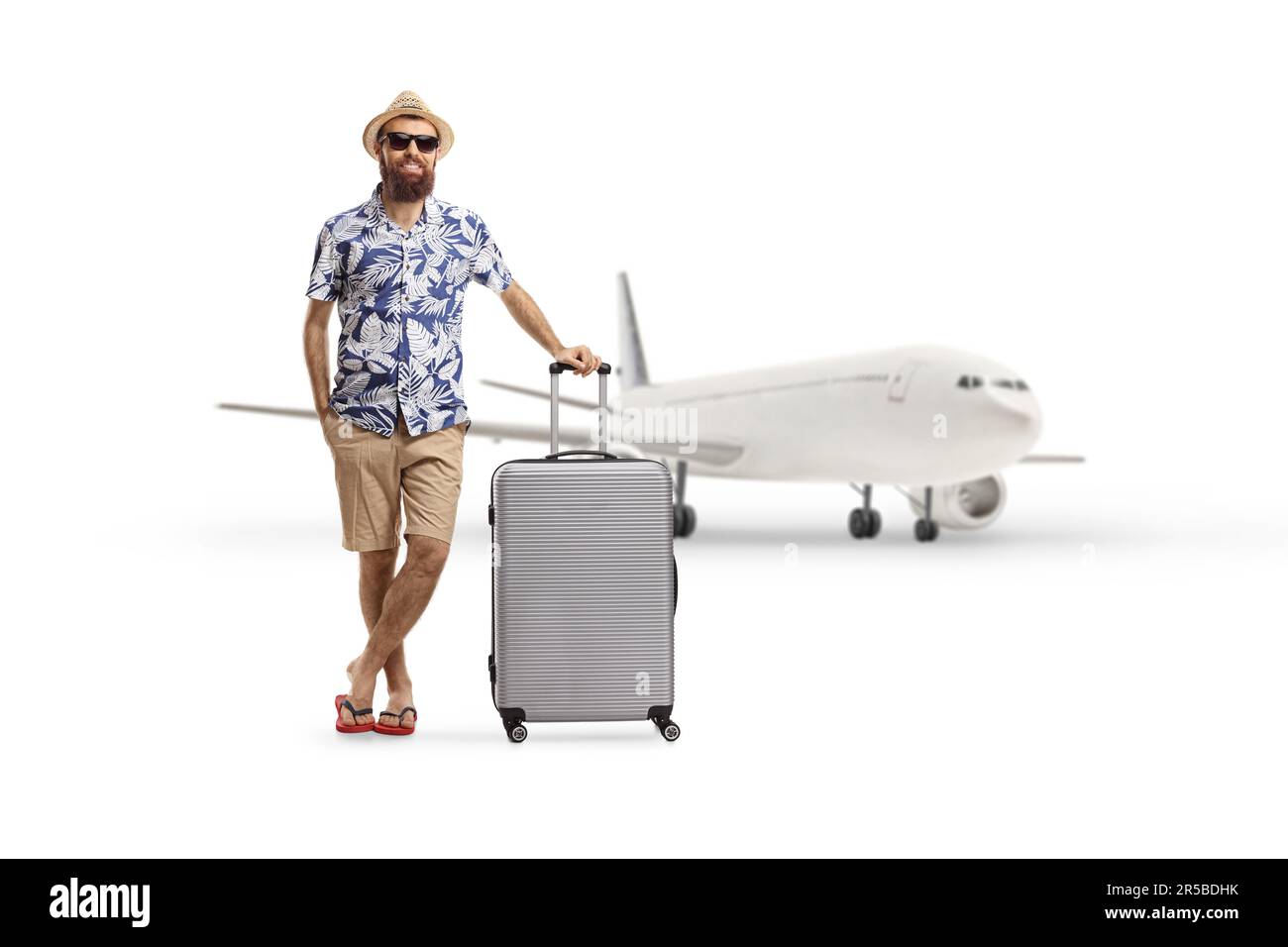 Full length portrait of a tourist posing with a suitcase in front of an aircraft isolated on white background Stock Photo