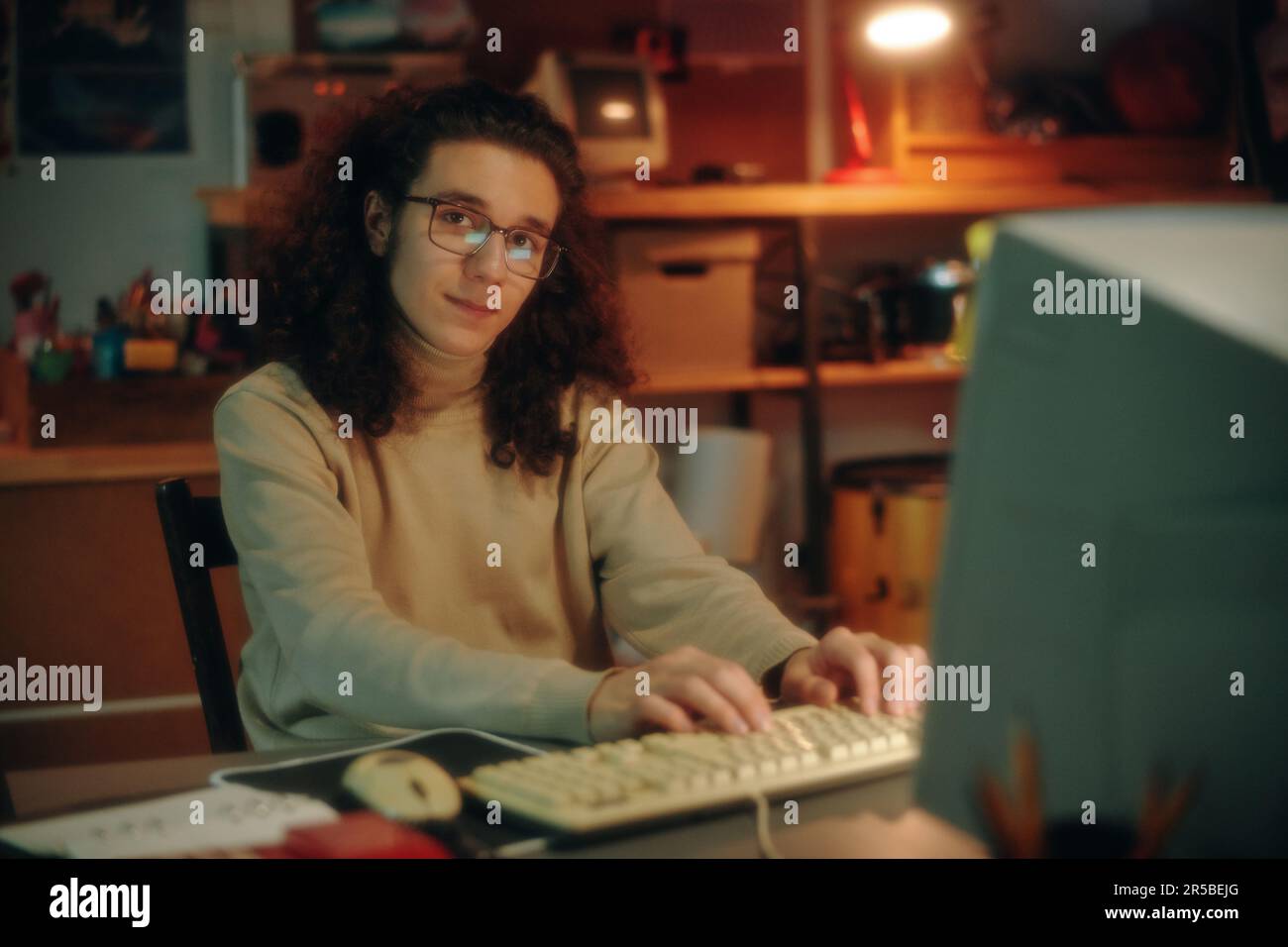Portrait of young programmer in eyeglasses looking at camera while developing new software on computer at table Stock Photo