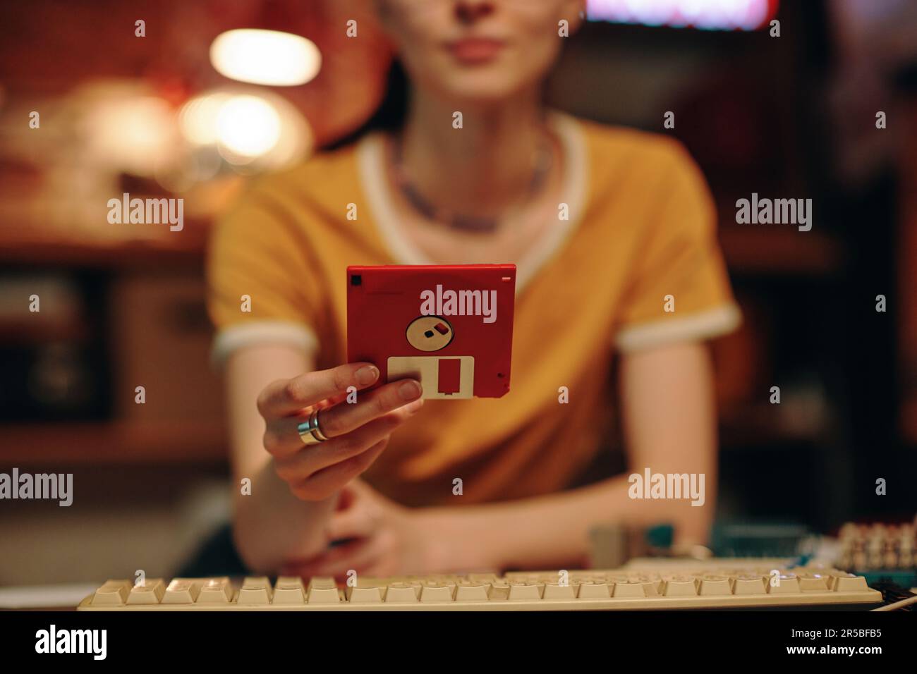 Close-up of young woman saving information on floppy disk while working on computer Stock Photo