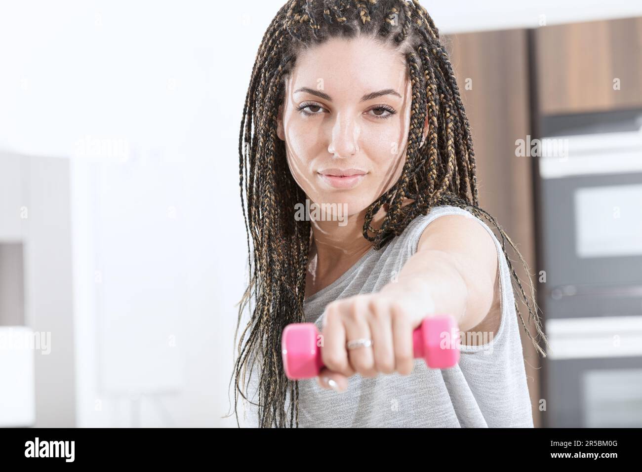 At home, a sporty and fit young woman with box braids carves out space