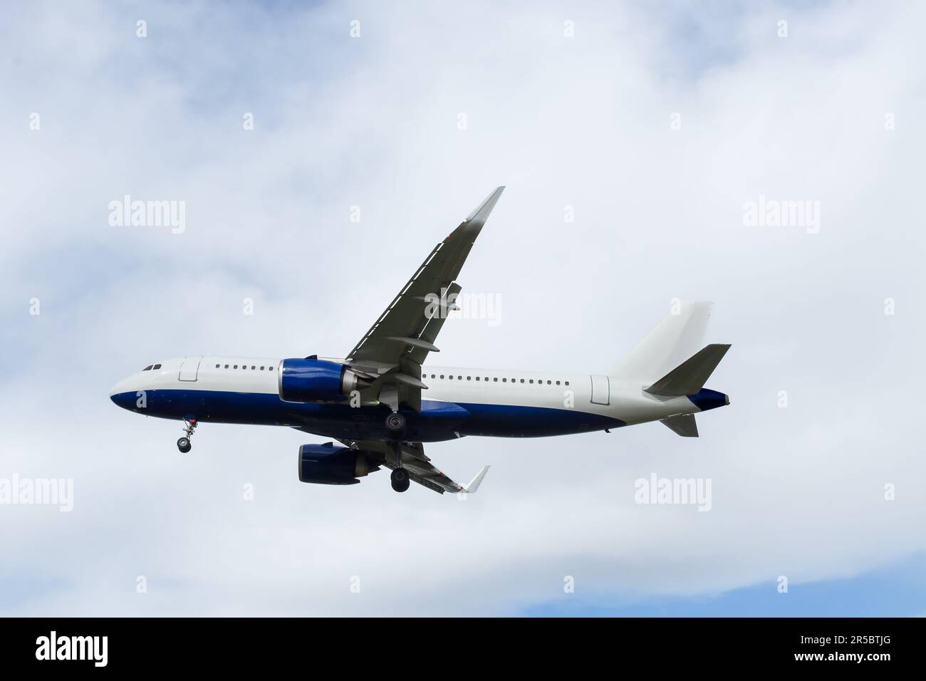 The plane flies in the blue sky with clouds. Stock Photo