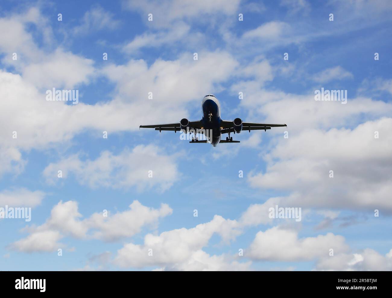 Beautiful background with a flying plane in the blue sky. Passenger aircraft with landing gear extended in the sky. Travel concept with copy space Stock Photo