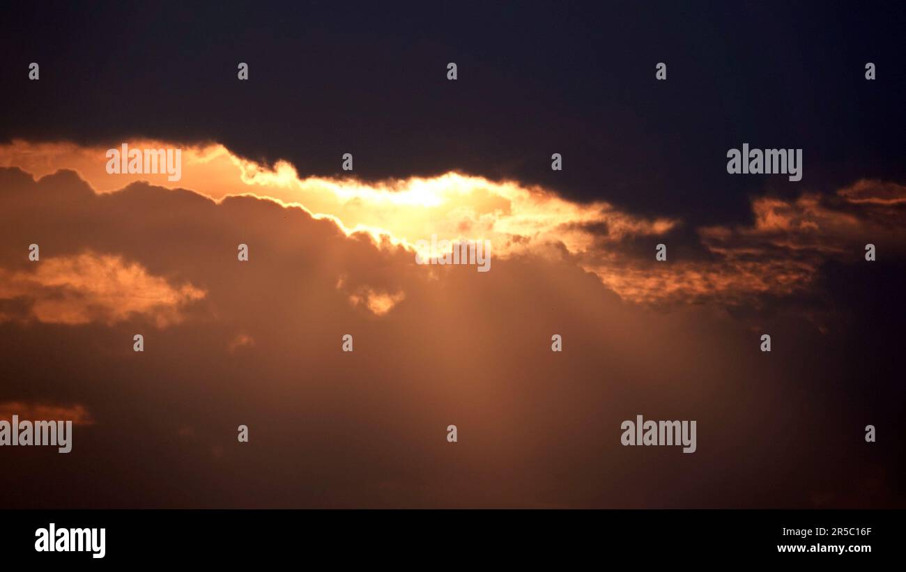 A view of sun rays shining through the clouds during a stunning sunset ...