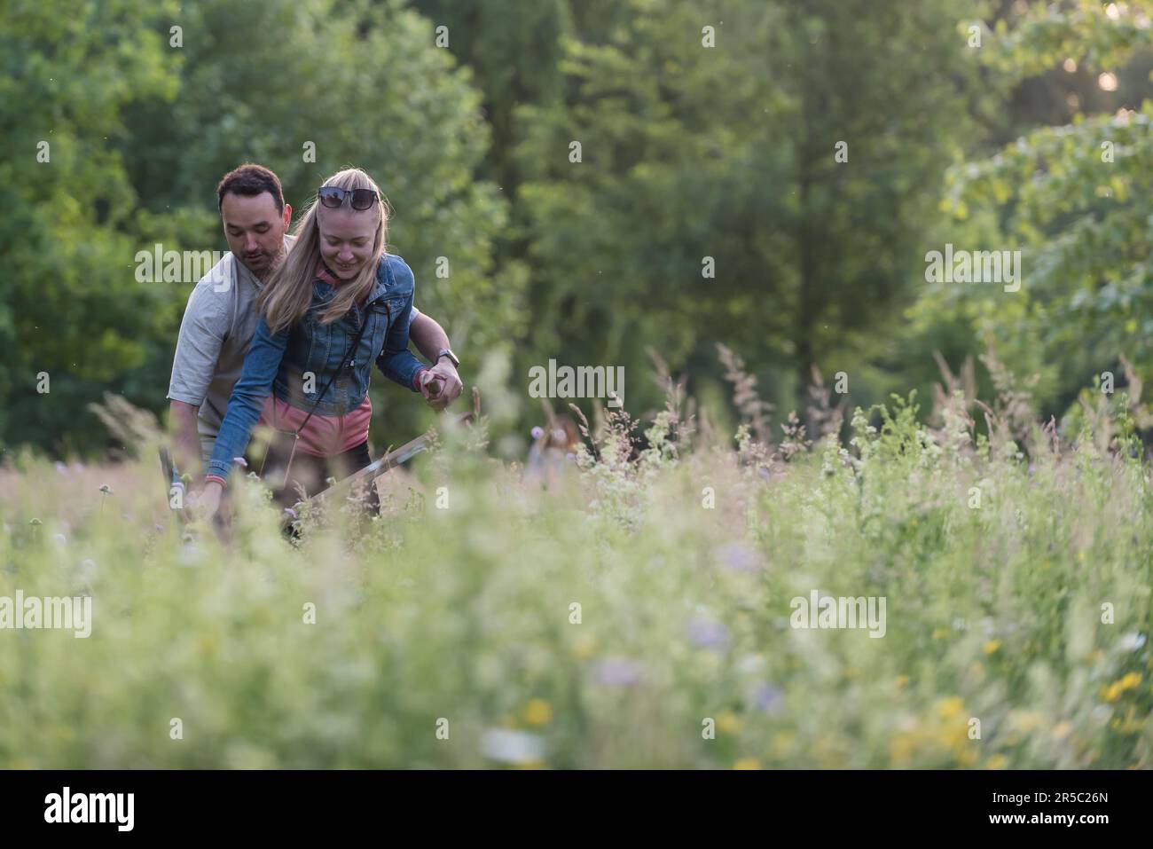 A couple uses a scythe to cut down the meadow. Around fifty locals
