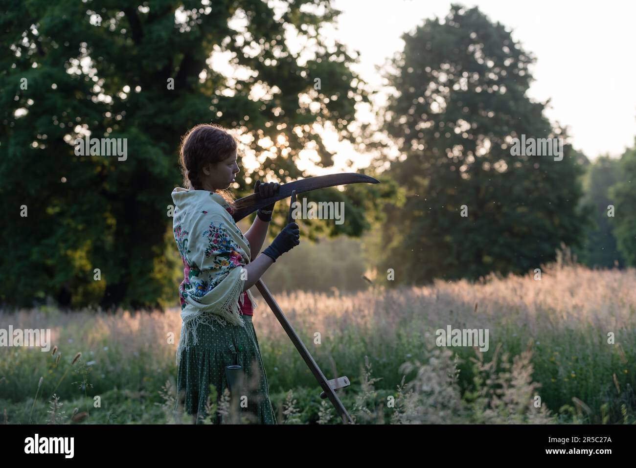 A woman dressed in traditional working outfit sharpens the scythe