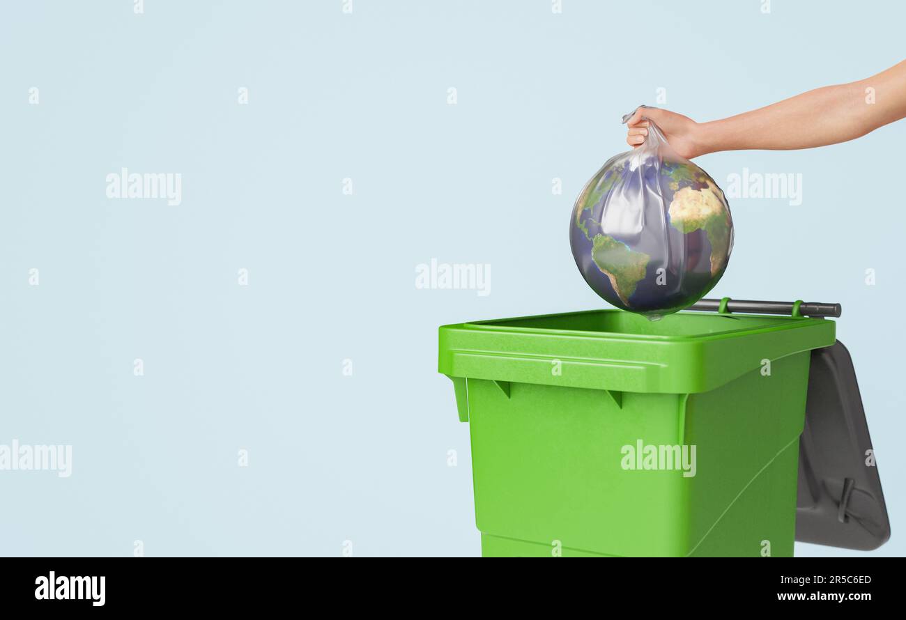 An adult hand reaching out to place a round ball into a green garbage bin Stock Photo