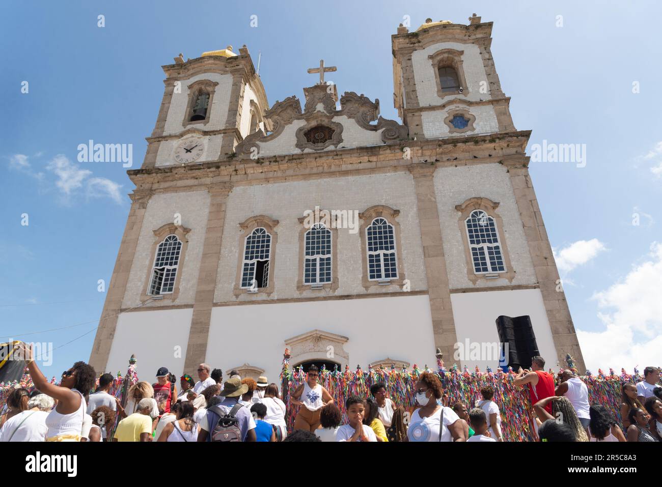 An old European style church with ornamental architecture painted in white stands tall and proud in front of a large crowd of onlookers Stock Photo