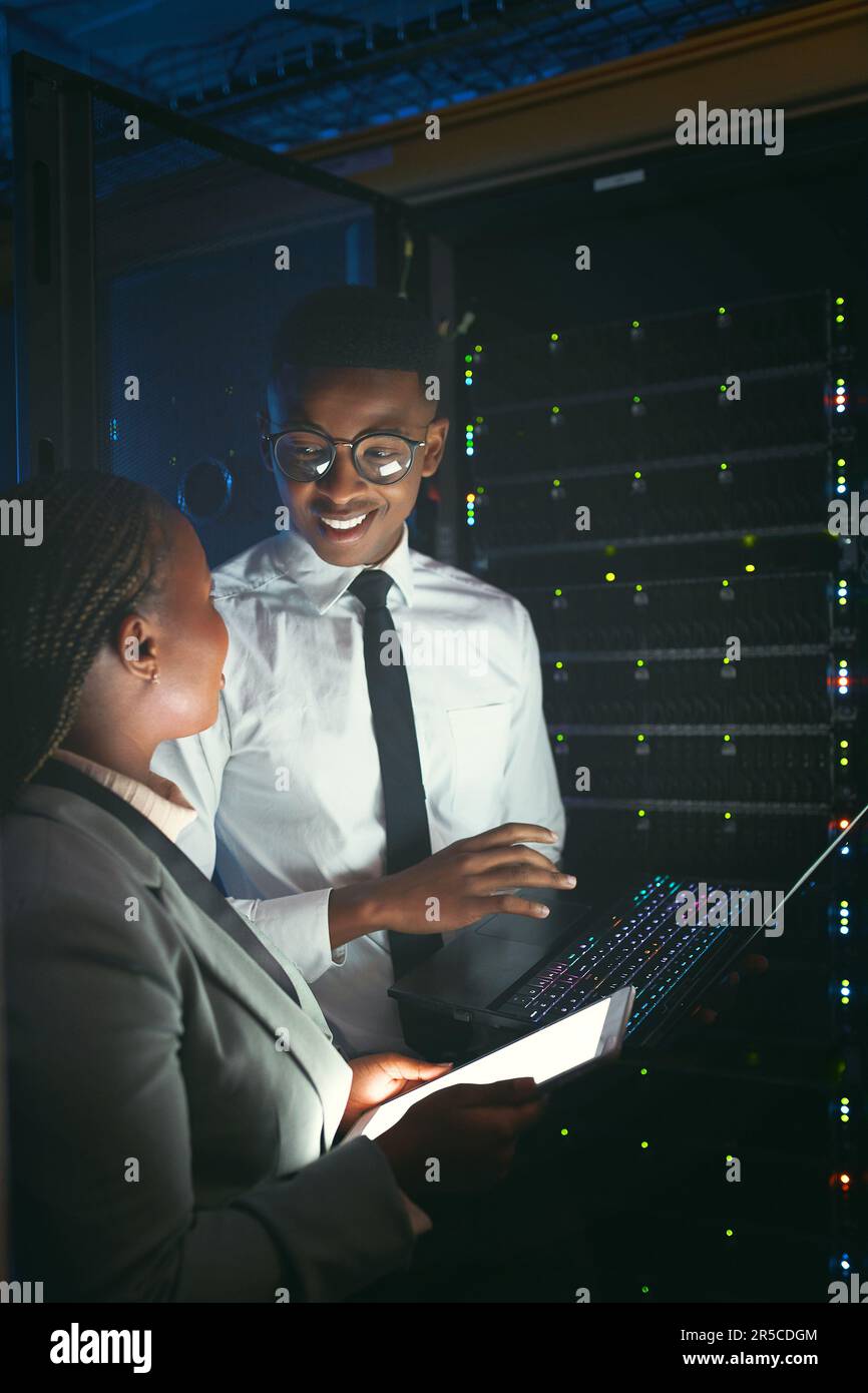 Sharing technical knowledge. two young IT specialists standing in the server room and having a discussion while using a technology. Stock Photo