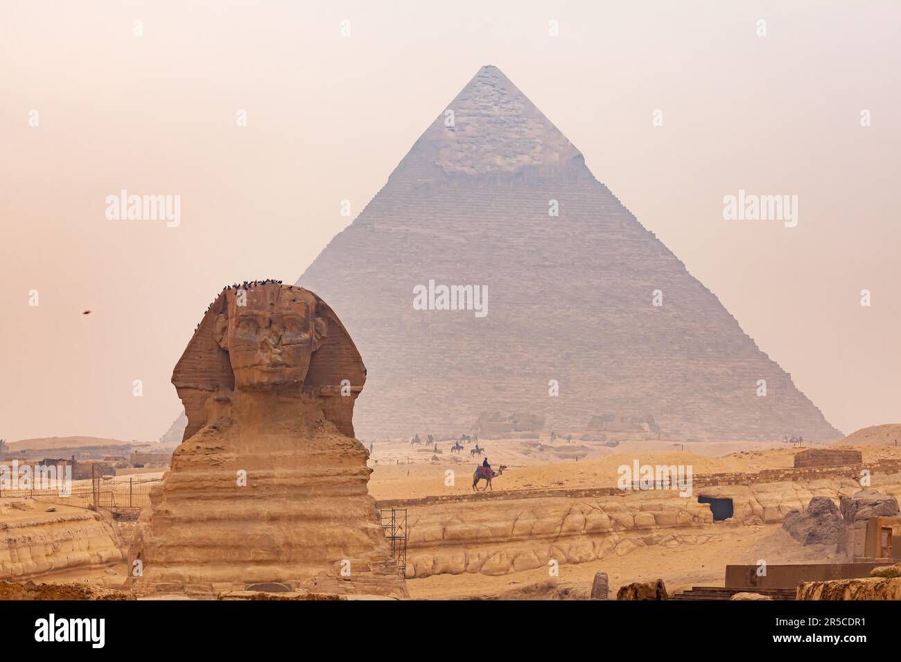 View of Sphinx in The Giza Plateau with The Great Pyramid of Giza or The Pyramid of Khufu in the background in hazy day, Cairo, Egypt Stock Photo