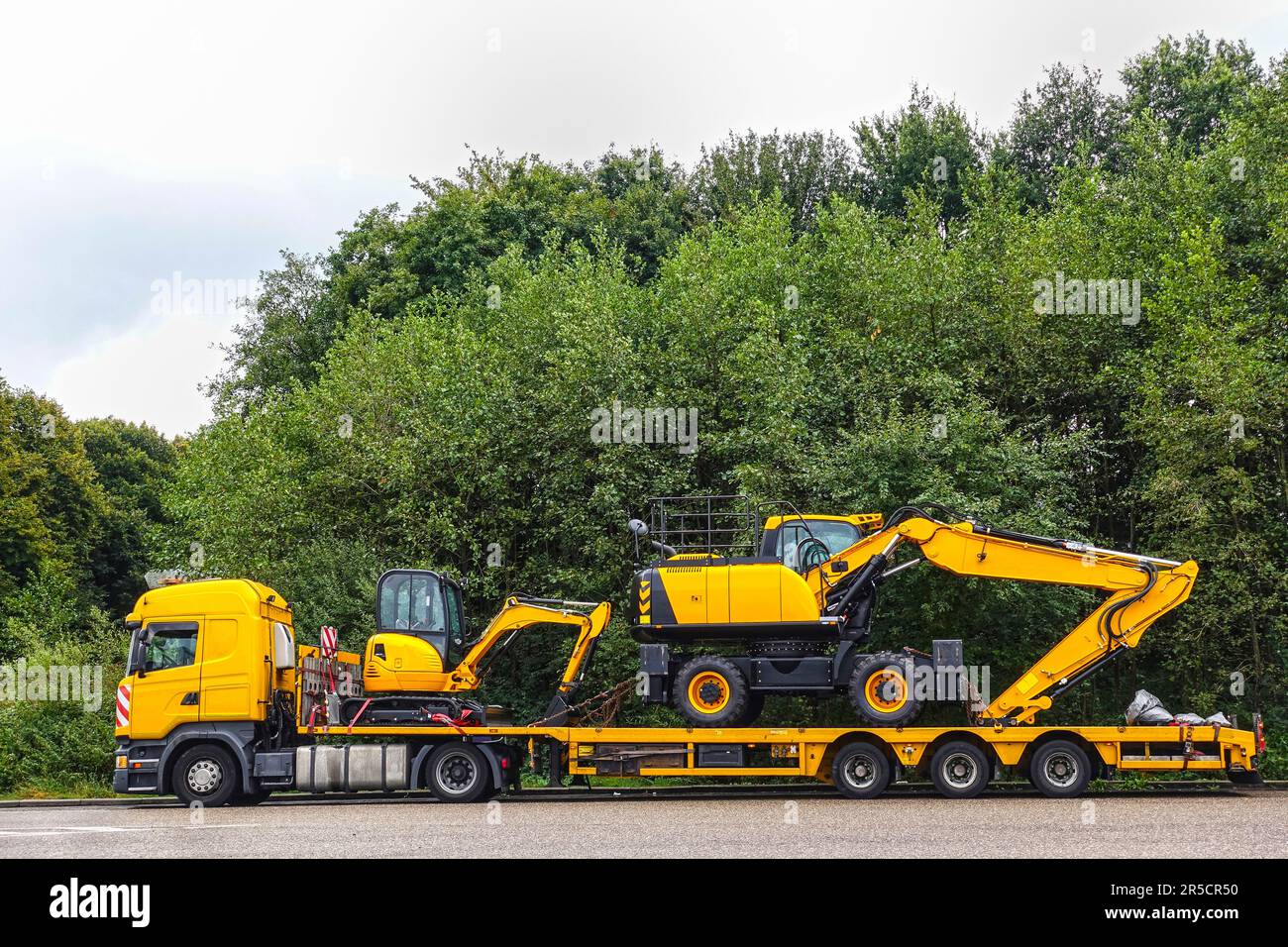 Low loader trailer carrying two excavators parking on a public truck parking area of a truck stop. Stock Photo