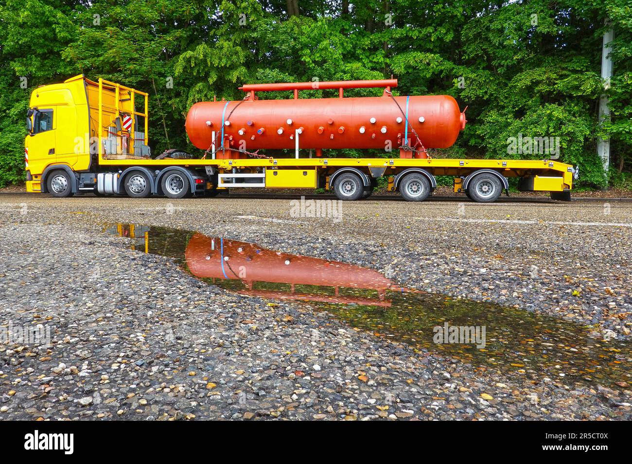 Big truck with a low platform trailer carrying a huge steel container