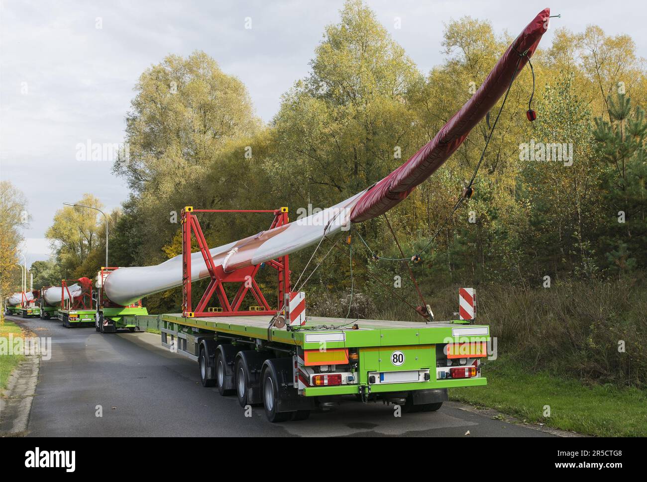 Roadside parking convoy of special trucks with oversize loads transporting rotor blades for wind power plant turbines Stock Photo