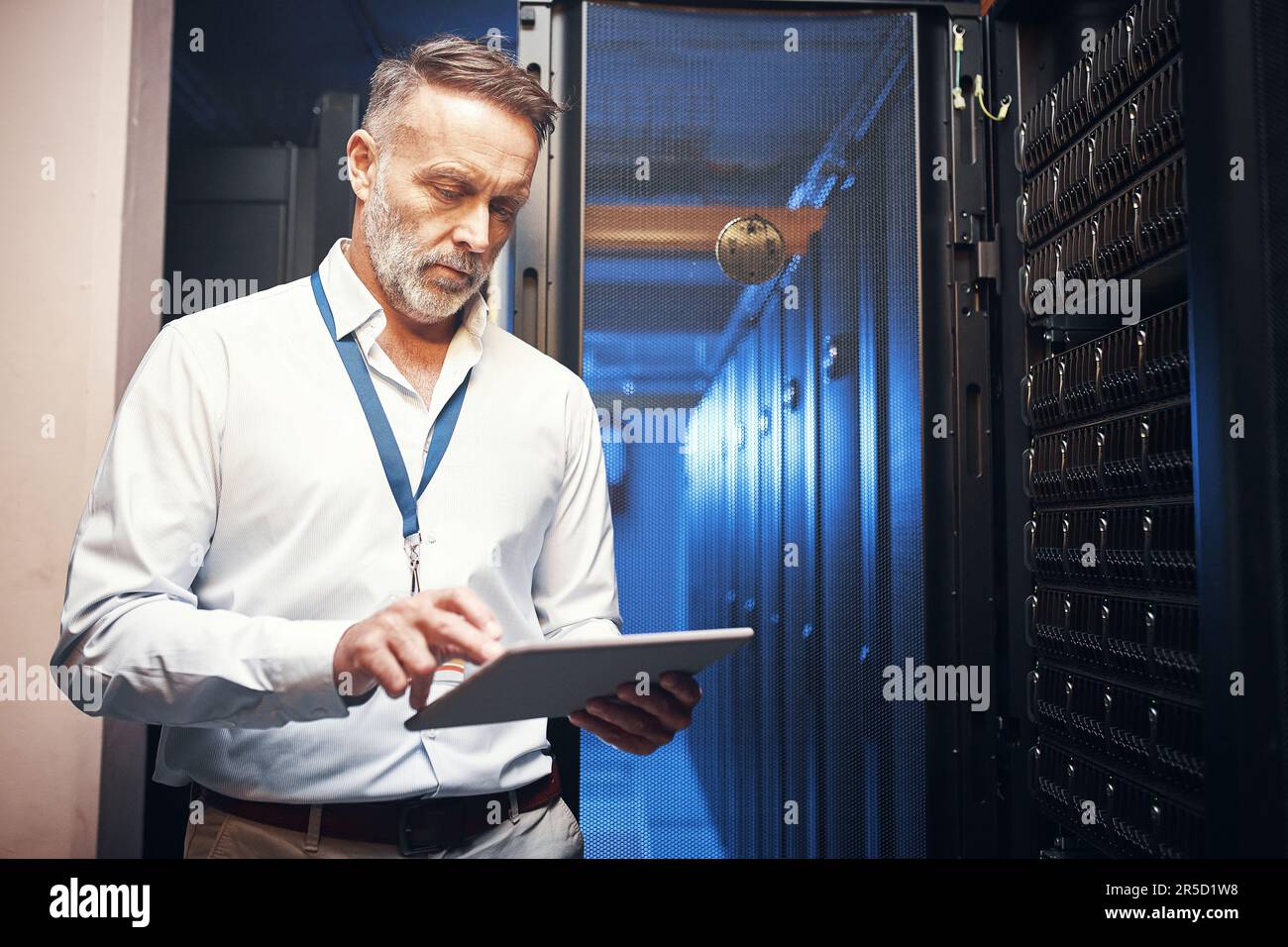 Serving up some serious safety points. a mature man using a digital tablet while working in a server room. Stock Photo
