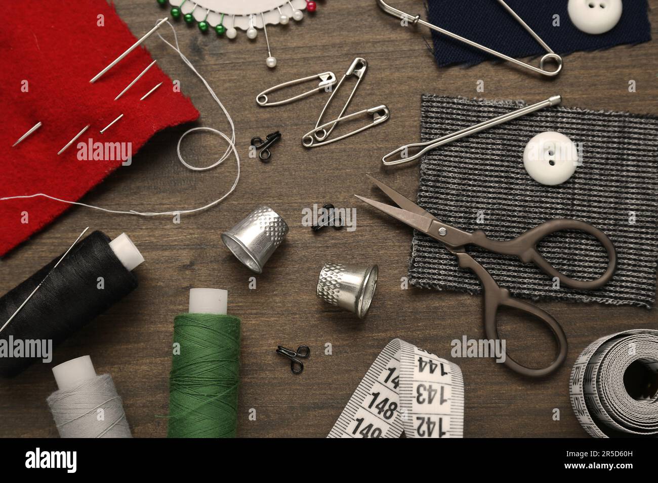 Flat lay composition with thimbles and different sewing tools on wooden table Stock Photo