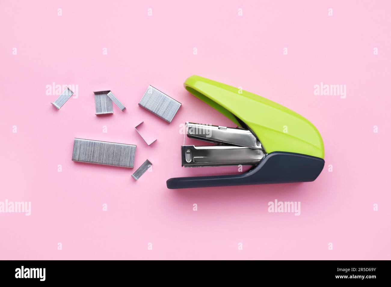 New bright stapler with staples on pink background, fat lay. School