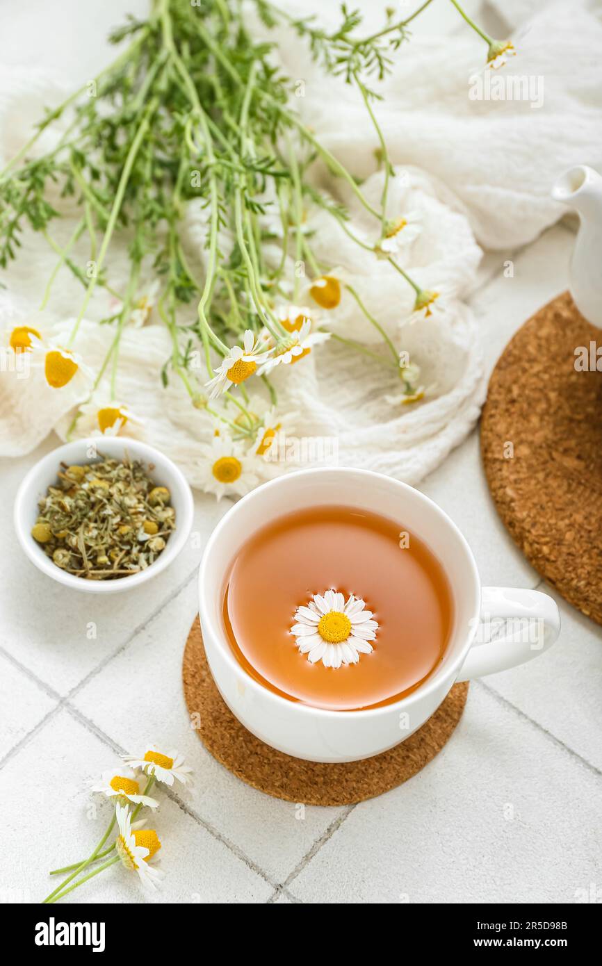 Cup of hot chamomile tea on white tile background Stock Photo - Alamy