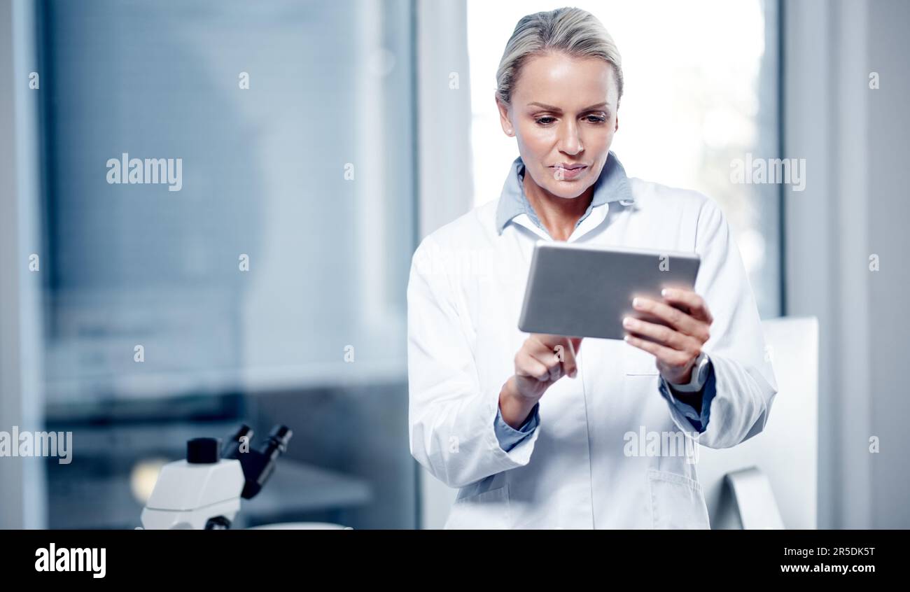Processing scientific data on her device. a mature scientist using a digital tablet while working in her lab. Stock Photo