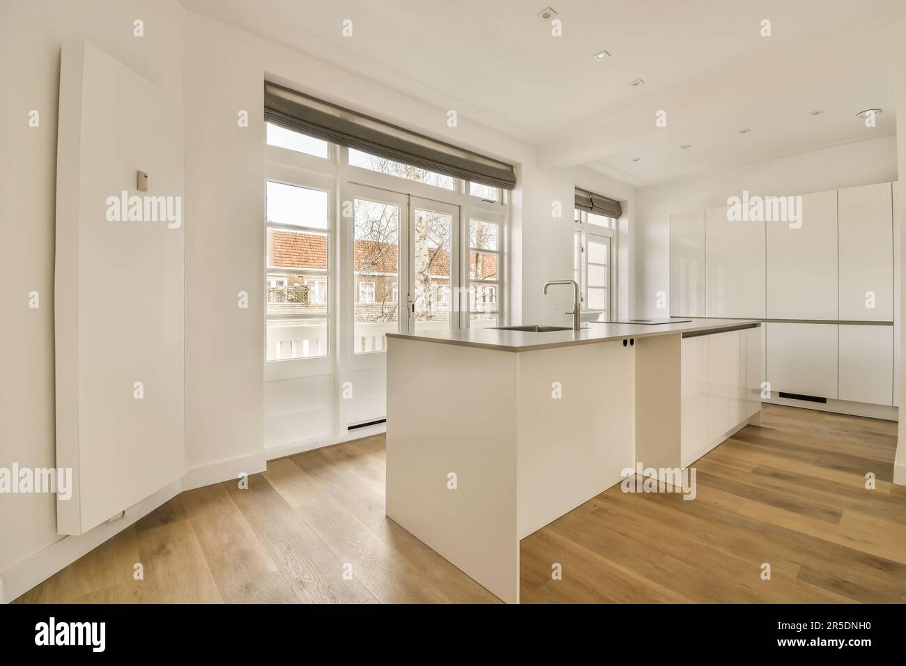 an empty kitchen with white cabinets and hardwood flooring in the ...