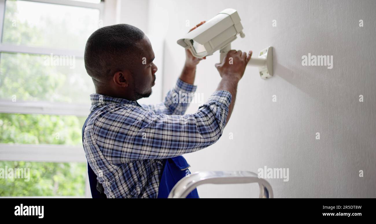 Close-up Of Technician Adjusting CCTV Camera On Wall Stock Photo