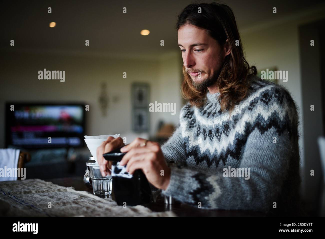 Coffee for one. a young man preparing coffee in his kitchen. Stock Photo