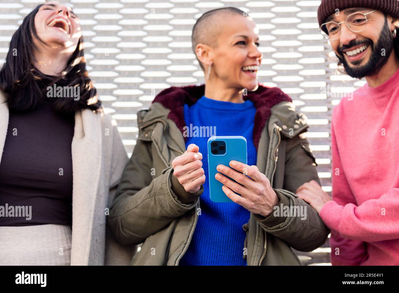 three young friends laughing using a phone Stock Photo