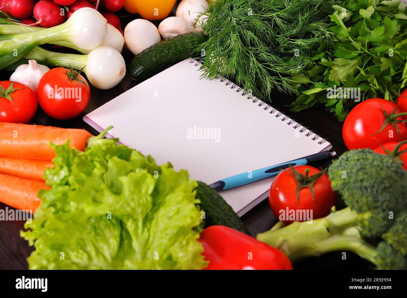 recipe book with vegetables and herbs on wooden table Stock Photo