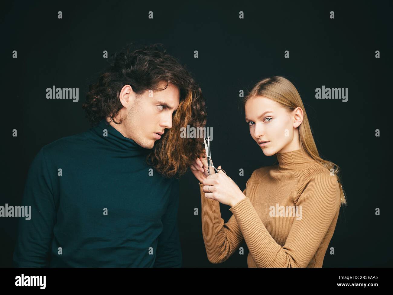 Girl scheming an evil plan of cutting off a curly hair in a man. A smart wily woman has wonderful schemes like a crook of a friend, a dark background Stock Photo