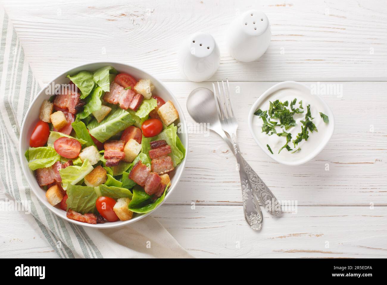 BLT Salad has a homemade ranch dressing, crispy bacon, croutons, lettuce and tomato closeup on the plate on the table. Horizontal top view from above Stock Photo
