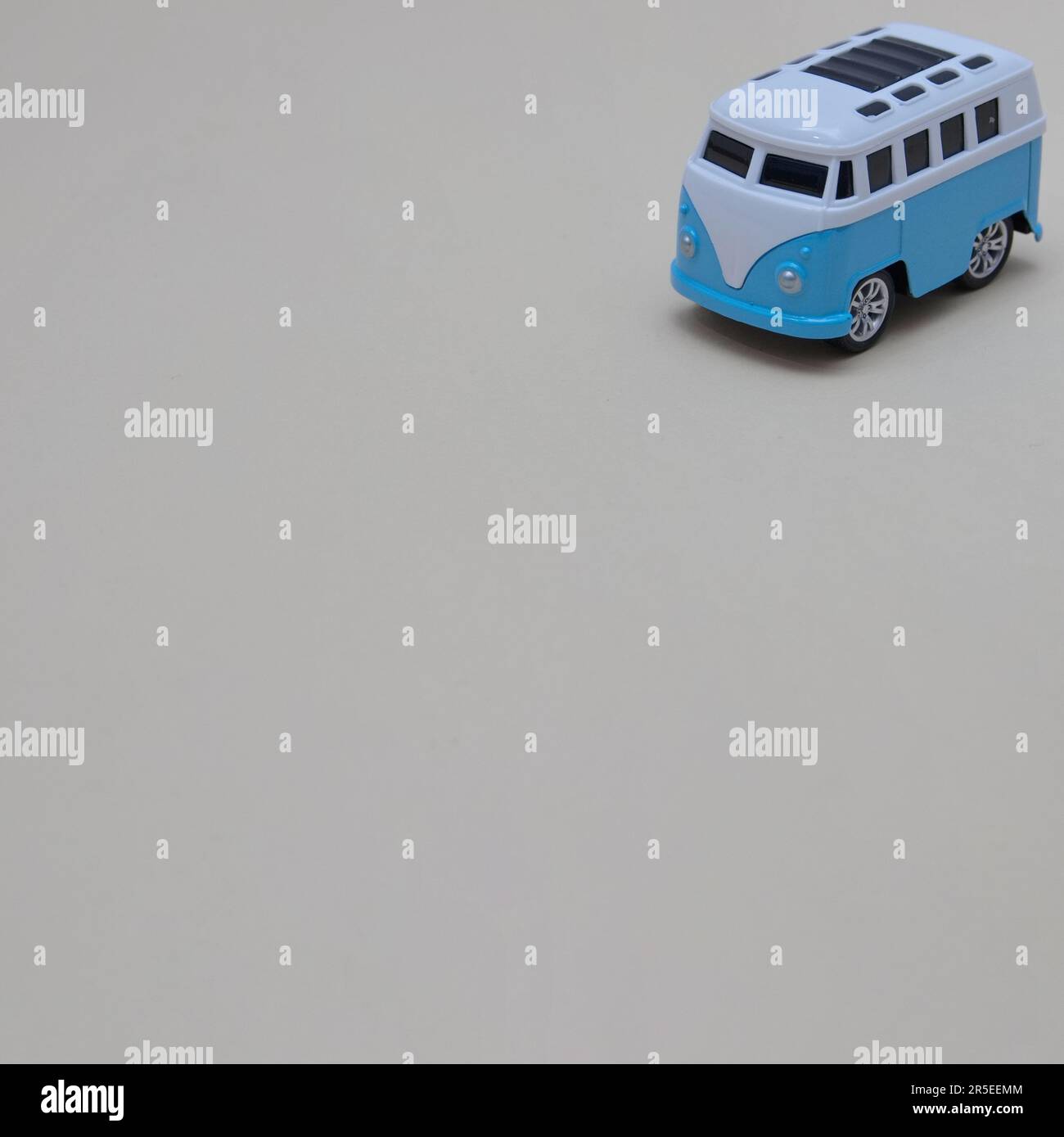 The blue and white van on a gray background is moving from the upper right corner. Copy space. Minimalistic van life concept. Stock Photo