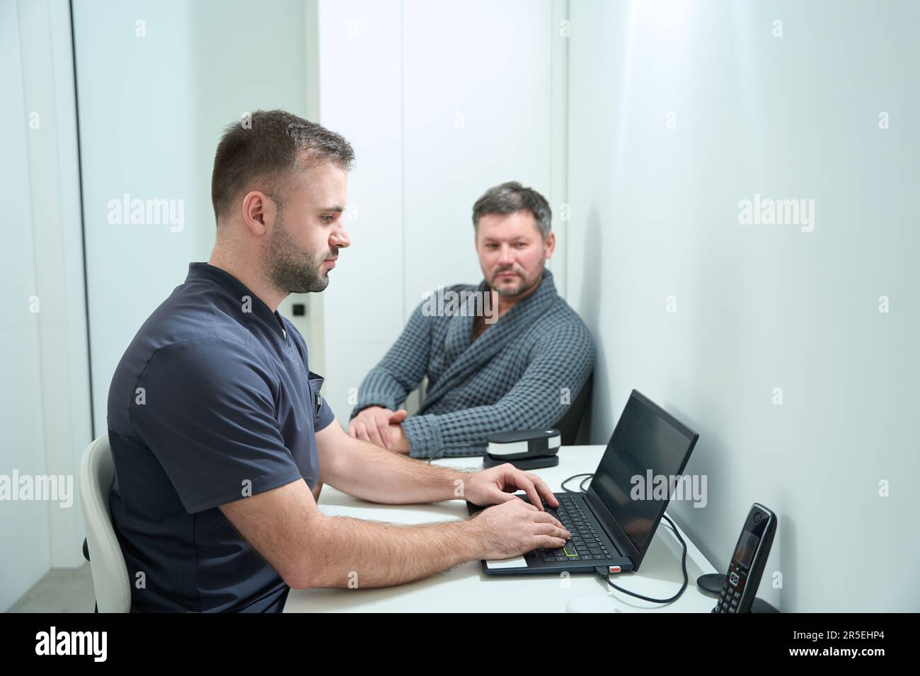 Male nutritionist is typing on a laptop at the workplace Stock Photo