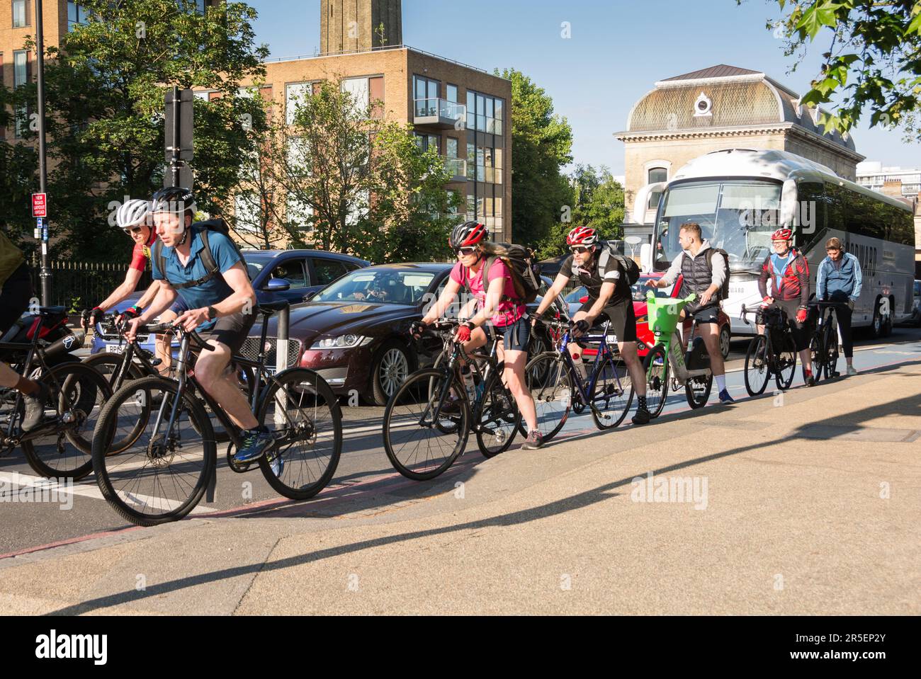 A group of colourful London cyclists on Cycle Superhighway 8 waiting for the traffic lights to change on Grosvenor Road, London, SW1, England, UK Stock Photo