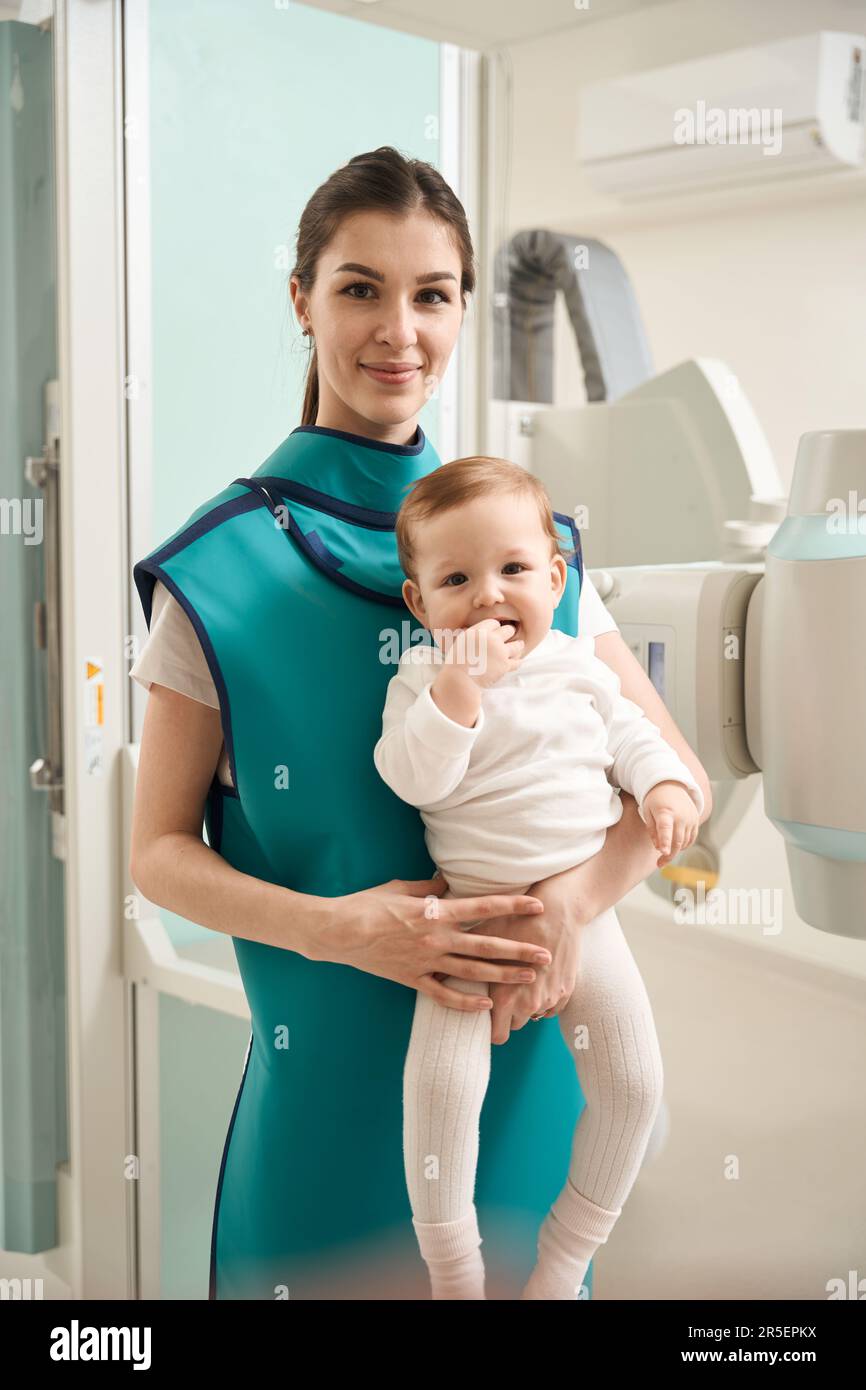 Contented young mother waiting with her infant for radiography ...