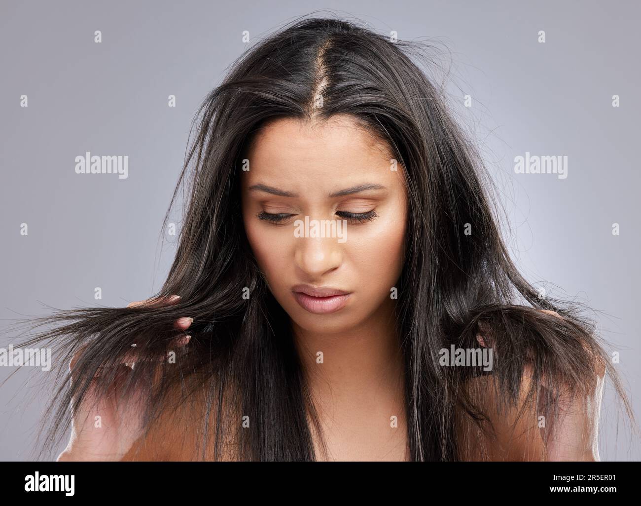 Hair, damage and face of woman in studio with worry for split ends, haircare crisis and weak strand. Beauty, hairdresser and upset female person with Stock Photo