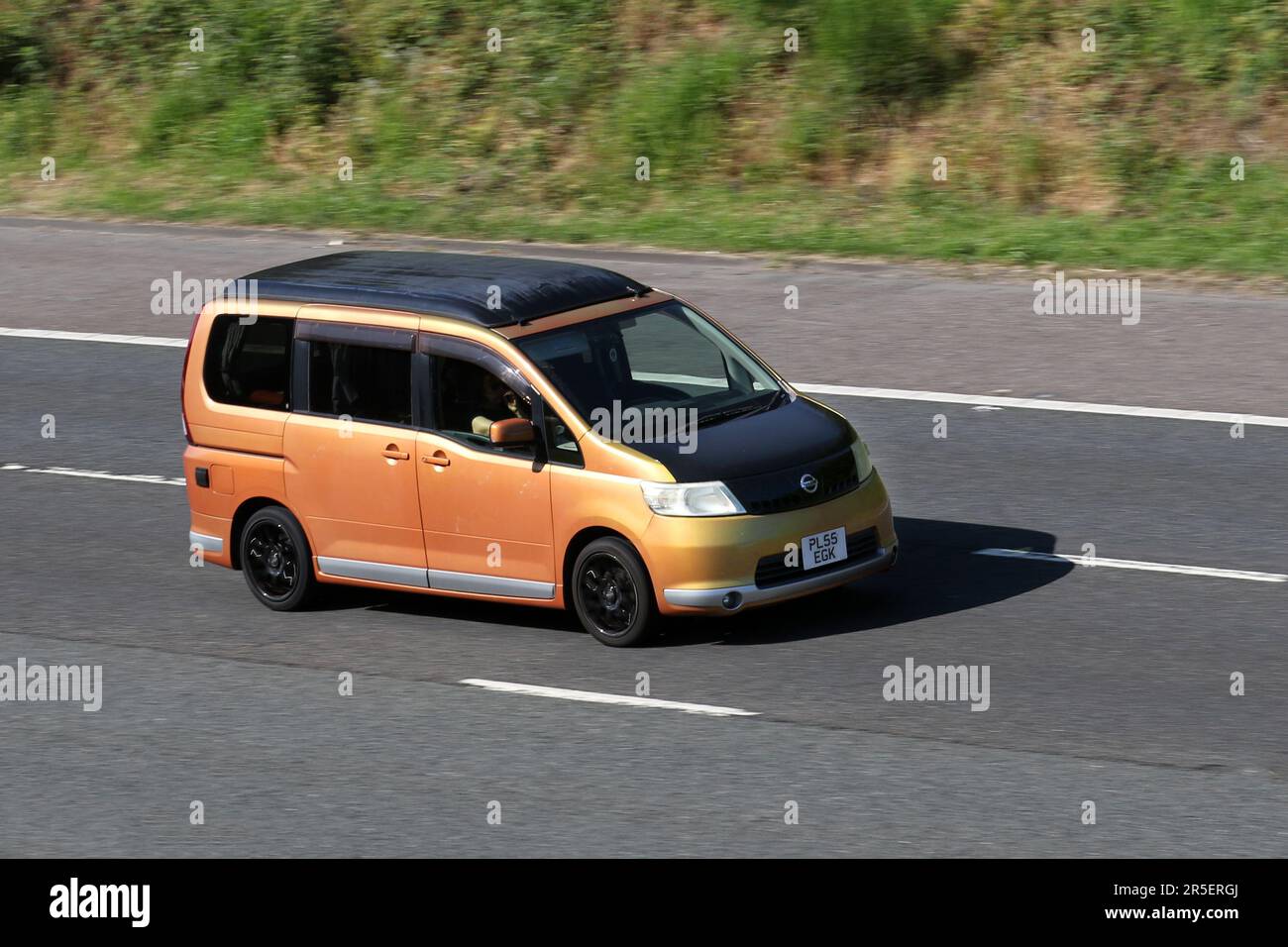 2006 Orange Black NISSAN SERENA 2000cc window van; travelling at speed on the M6 motorway in Greater Manchester, UK Stock Photo