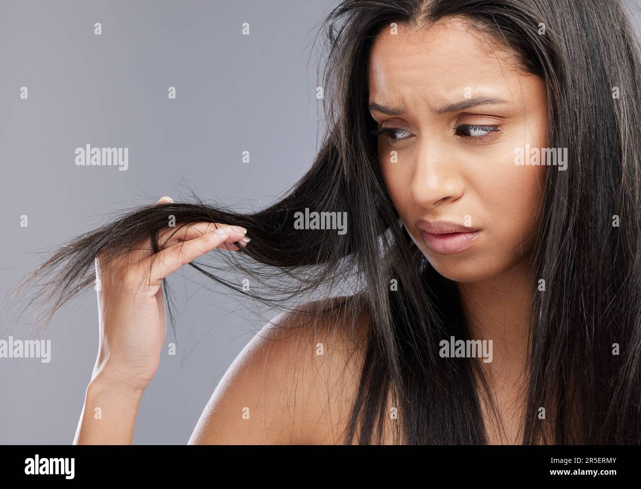 Hair, damage and face of woman worried in studio for split ends, haircare crisis and weak strand. Beauty, hairdresser and upset female person with Stock Photo