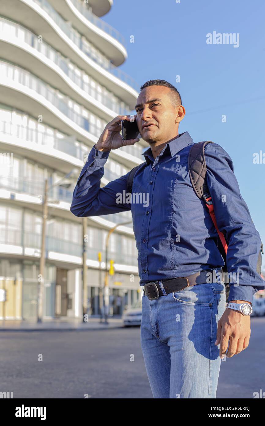 Portrait of young latino man in a city talking on a mobile phone. Stock Photo