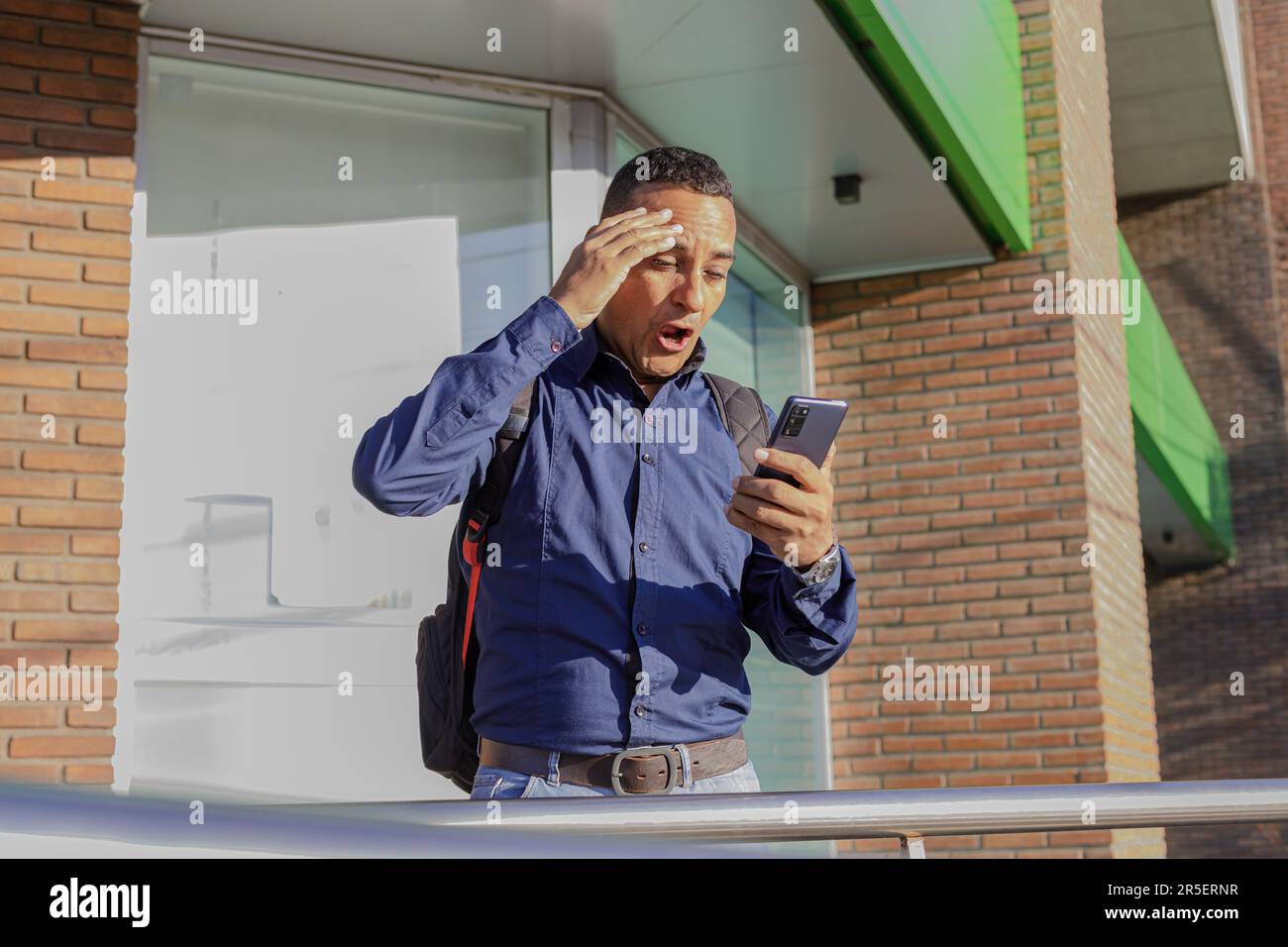 Young latino man looks surprised at his mobile phone. Stock Photo