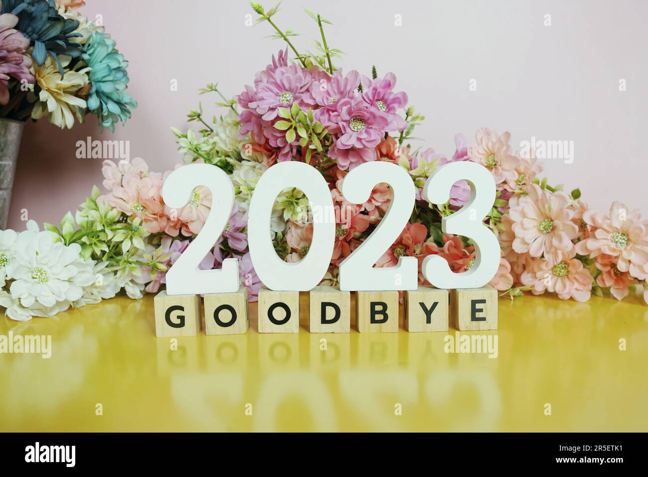 Goodbye 2023 alphabet letters with flower decoration on pink and yellow