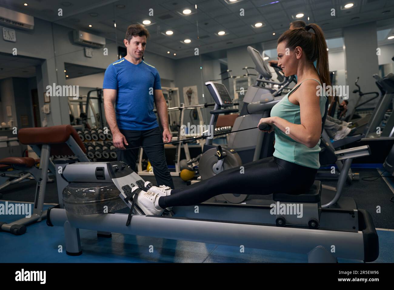 Female performing upper back exercise supervised by personal trainer Stock Photo Alamy