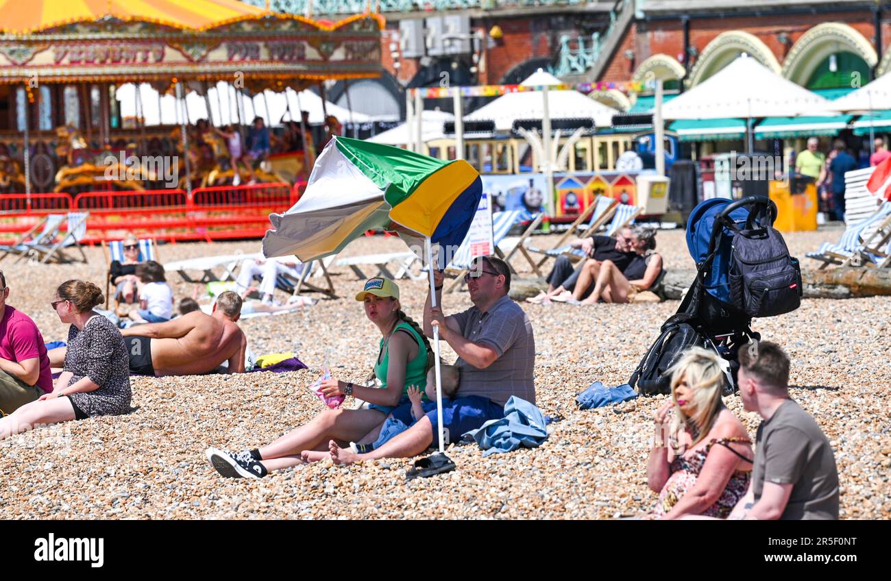 Brighton UK 3rd June 2023 - Time to get the beach umbrella out to get some shade on another hot sunny day in Brighton : Credit Simon Dack / Alamy Live News Stock Photo